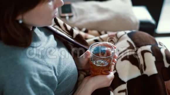 一个冷女人喝裹在毯子里的茶视频的预览图