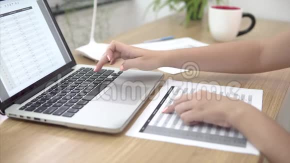 年轻的女商人在办公室工作场所使用笔记本电脑检查纸文件周围是纸视频的预览图