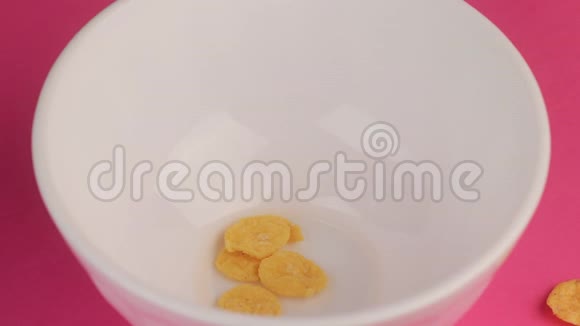 黄色早餐玉米片放在白色碗里粉红色背景视频的预览图
