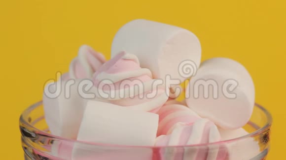 粉红色扭曲和白色棉花糖在玻璃罐黄色背景视频的预览图