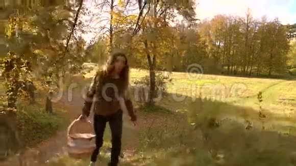 一个穿着棕色夹克背着篮子在秋天的树林里上山的黑发女孩爬山4KStedicam镜头视频的预览图