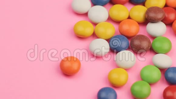 在粉红背景下合上一堆五颜六色的巧克力糖果视频的预览图