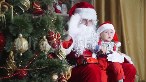 圣诞老人坐在一棵圣诞树后面和一个婴儿挥手视频的预览图