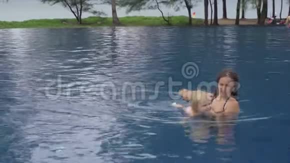 妈妈和一个两岁的女儿在海边的酒店游泳池里视频的预览图