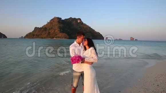 新娘和新郎拥抱站在水中对抗岛屿视频的预览图