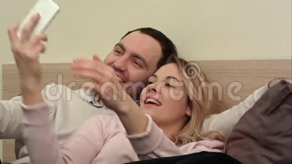 快乐的情侣在床上做鬼脸和自拍视频的预览图