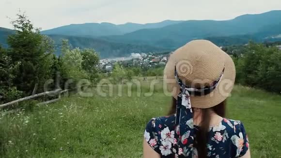 在乡村度假时妇女戴着夏季帽望着山的背景视频的预览图