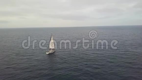 从蓝色海洋中的飞行无人驾驶游艇在多云天空中的空中景观视频的预览图