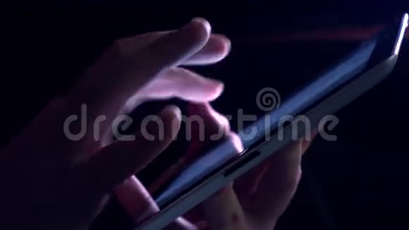 在黑暗的房间里给平板电脑做手势紫色发光触摸屏4K视频视频的预览图