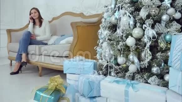 幸福的年轻女子拿着漂亮的礼物在圣诞树旁交谈视频的预览图