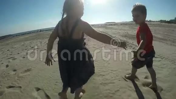 快乐的女孩和男孩赤脚在沙滩上奔跑视频的预览图