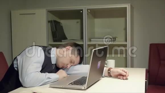 年轻英俊的男人躺在桌子上睡觉然后他突然醒来开始在电脑上工作视频的预览图