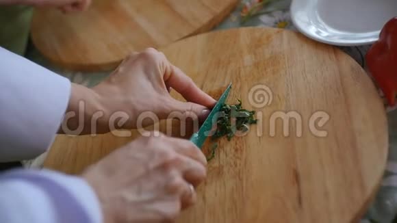 女人在厨房的餐桌上准备饭菜准备和切碎茂盛的绿叶蔬菜食品工业快关门视频的预览图