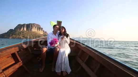 新娘和新郎在日出时乘长尾船漂到岛上视频的预览图