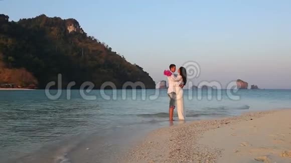 新娘和新郎拥抱站在水中对抗岛屿视频的预览图