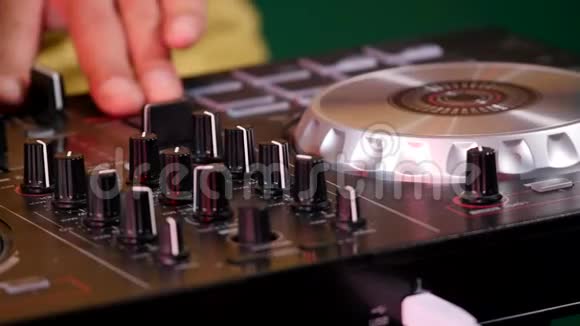 一个男性音乐艺术家手推垫和抓挠控制台的特写镜头DJ混合音乐视频的预览图
