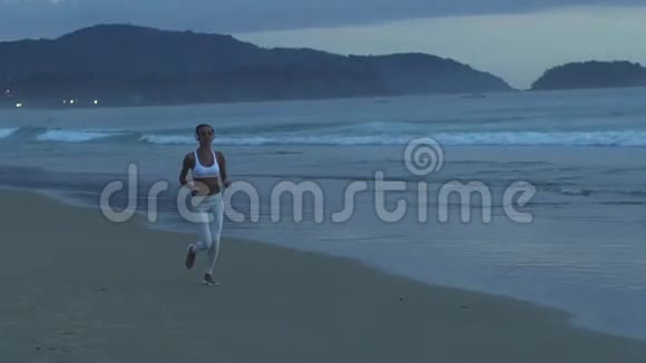 傍晚在热带海滩上跑步的健身妇女视频的预览图
