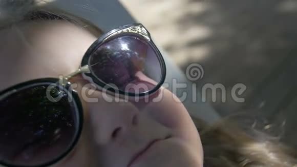一个戴墨镜的可爱金发小女孩的特写镜头视频的预览图