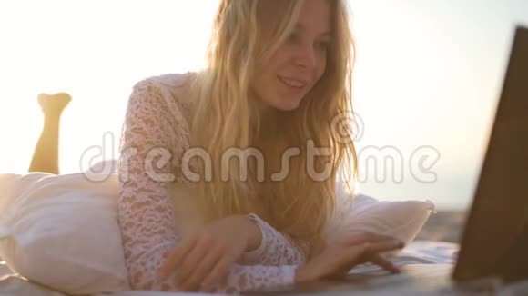 女孩在海滩上用笔记本电脑视频的预览图