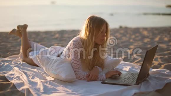 女孩在海滩上用笔记本电脑视频的预览图