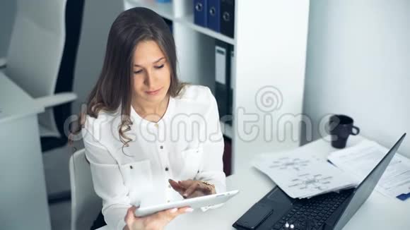 漂亮的女商人在办公室里用数码平板电脑视频的预览图