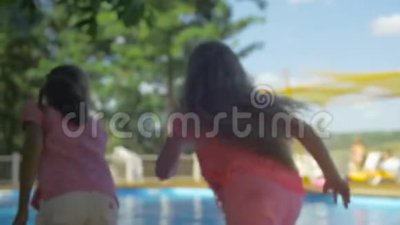阳光明媚的一天两个光着脚的小女孩沿着游泳池奔跑视频的预览图