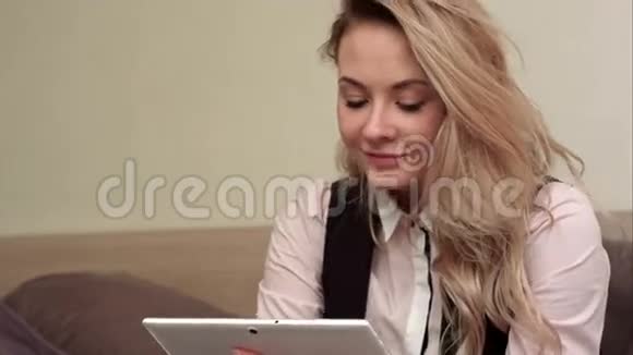 年轻的商务女性坐在酒店的卧室里通过平板电脑进行视频聊天讨论问题视频的预览图