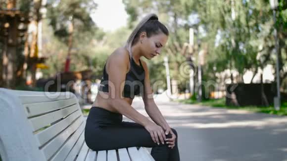 女运动员跑步者在疼痛中触摸膝盖健身妇女在夏季公园跑步视频的预览图