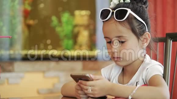 小女孩黑发拉蒂娜坐在咖啡馆里玩智能手机游戏愤怒不开心视频的预览图