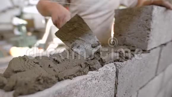 用泥刀在建筑工地上对砖匠的特写镜头视频的预览图