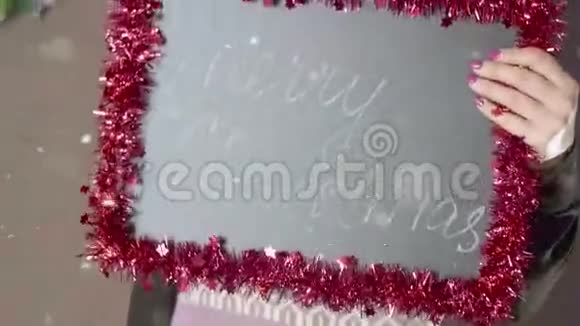 女性手拿着写着圣诞快乐的黑板然后送礼物视频的预览图
