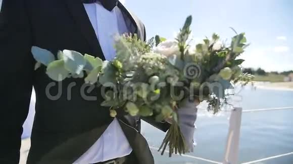 新郎在湖边慢动作地捧着结婚花束视频的预览图