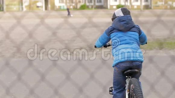 一个穿着运动夹克戴着黑色眼镜的男孩骑着自行车在电网后面视频的预览图