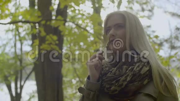 秋天公园里一个美丽的梦幻的女孩的肖像金发碧眼一片叶子视频的预览图