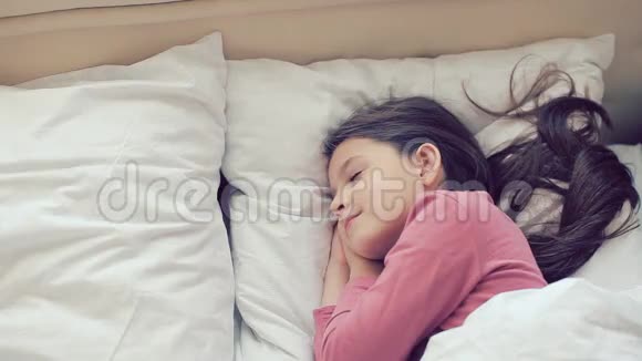 小女孩睡觉女孩在睡觉小女孩穿着睡衣睡在孩子们房间的床上视频的预览图