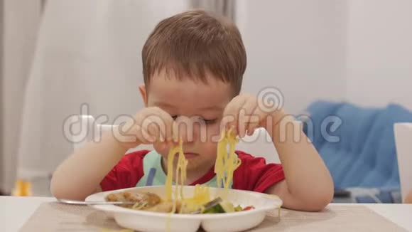 小孩子坐在一张桌子旁吃自己的意大利面可爱的小猫可爱的小宝宝视频的预览图