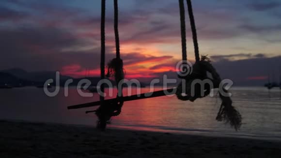 在美丽的夕阳下一根绳子从靠近大海的树上挂着慢动作3840x2160视频的预览图
