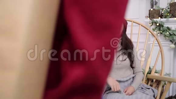 年轻的亚洲女人坐在家里客厅里用灰色毯子包裹的椅子上视频的预览图