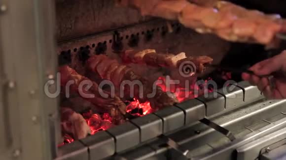一个人把肉串放在燃烧的煤块上视频的预览图