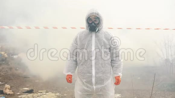 身穿生化防护服戴着防毒面具的男子站在烟雾中视频的预览图