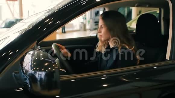 豪华轿车沙龙里的布鲁内特女士手握方向盘视频的预览图