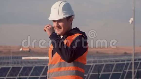 一个戴着头盔的人在一家太阳能发电厂的背景下拿着一平板电脑视频的预览图
