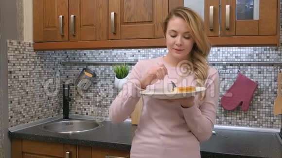 迷人的年轻金发女人在现代厨房里打破饮食和吃蛋糕视频的预览图