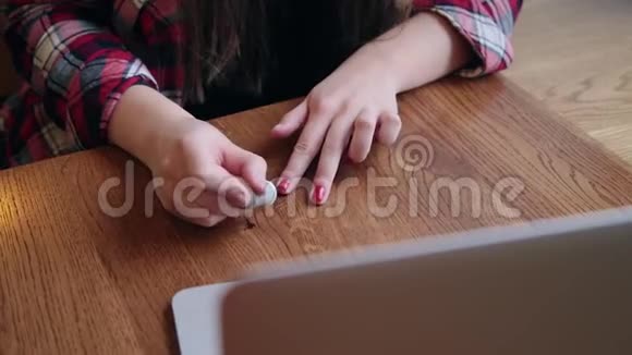 一位漂亮的女商人坐在一张桌子旁在咖啡馆里拿着笔记本电脑画着她的指甲视频的预览图
