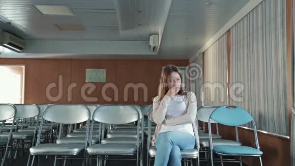 女人坐在空荡荡的会议厅的椅子上视频的预览图