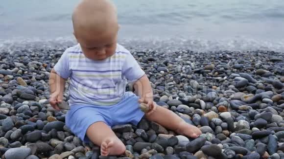 新生儿男孩在风和日丽的海边玩石头视频的预览图