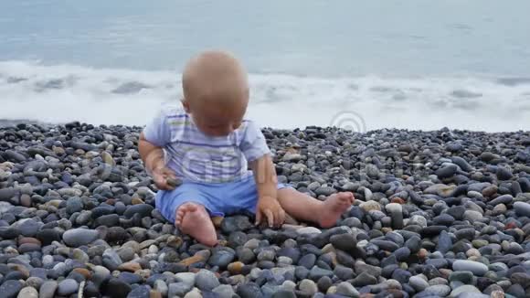 新生儿男孩在风和日丽的海边玩石头视频的预览图