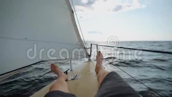 译文一个人的腿在游艇的鼻子上人们乘船沿着大海向远处浪去帆是视频的预览图