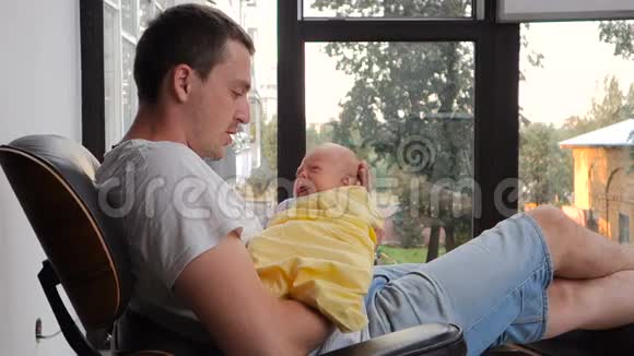 在父亲怀里裹着黄色床单的新生儿视频的预览图