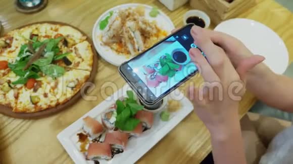 特写镜头女手在餐厅的智能手机上拍披萨视频的预览图